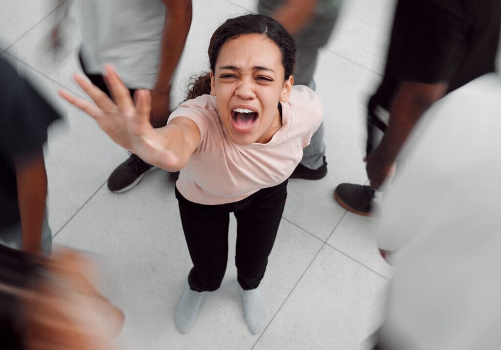 Shot of a young woman experiencing mental illness while being surrounded by people inside.